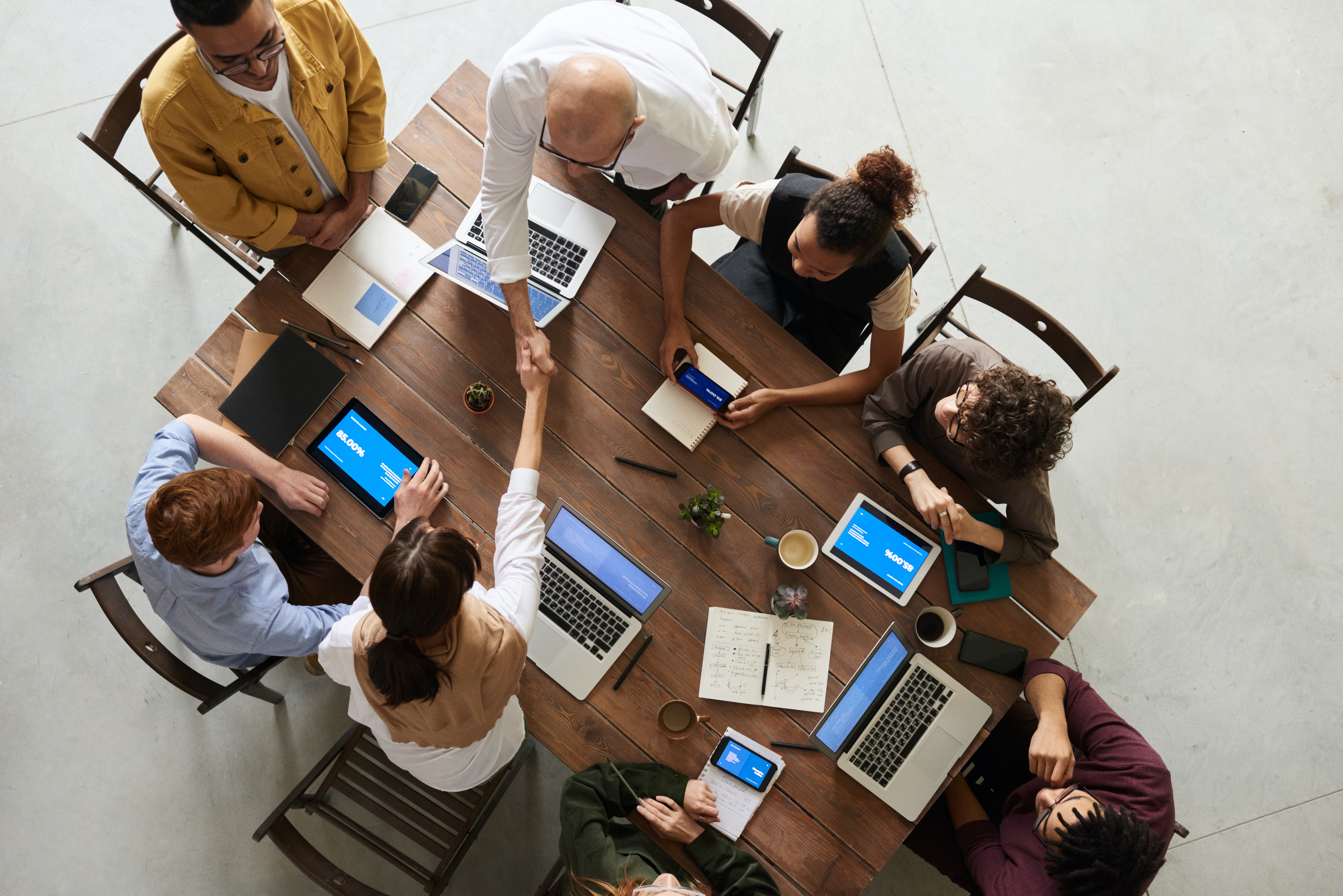 Eight people sat around a table working together in an office.