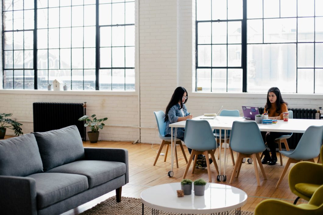 Bright, open office space with two employees working separately at a table